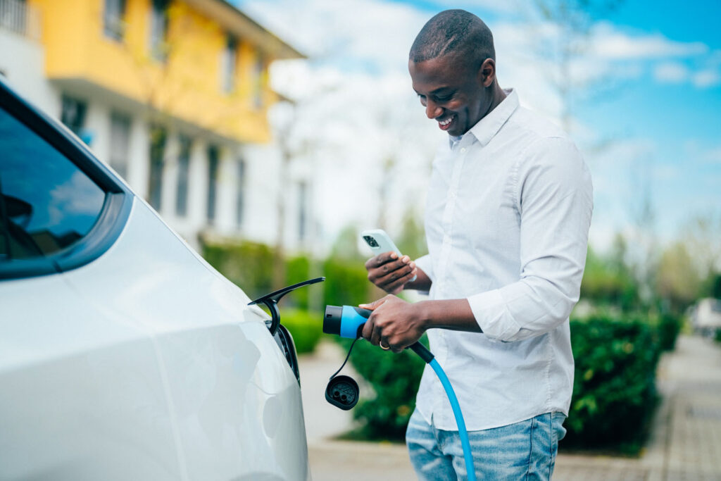 Man texting on phone while charging electric car