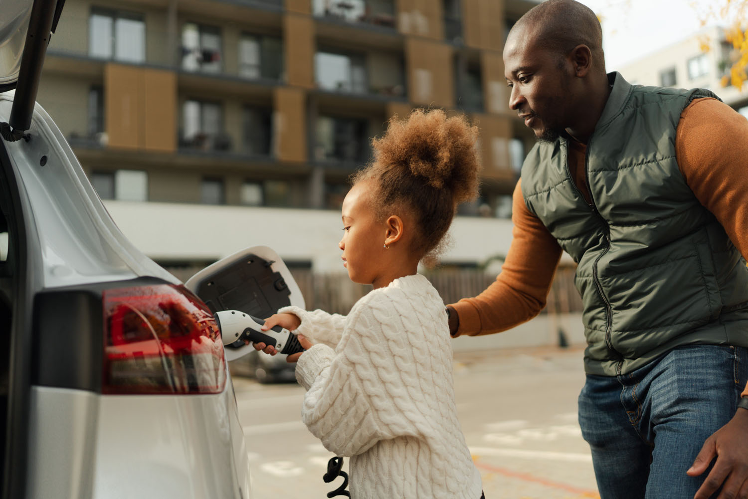 Close-up of father with his daughter charging their electric car.