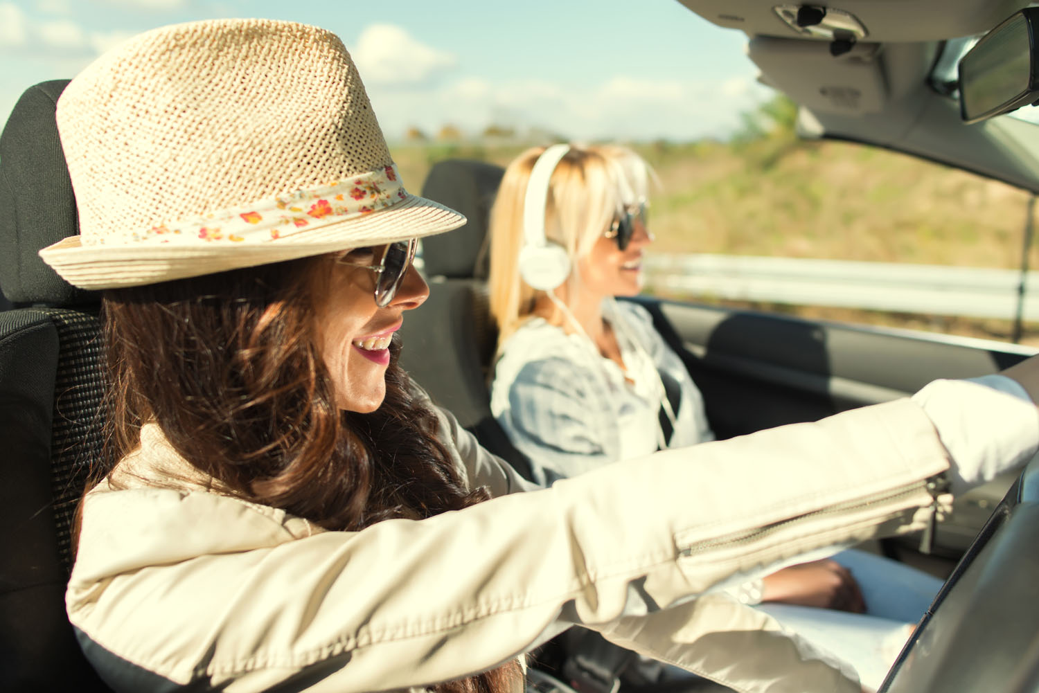 Happy women having fun on a road trip in convertible