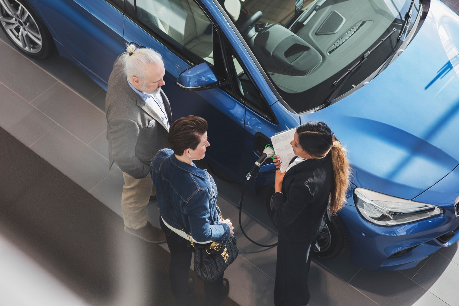 High angle view of saleswoman talking to customers at car showroom