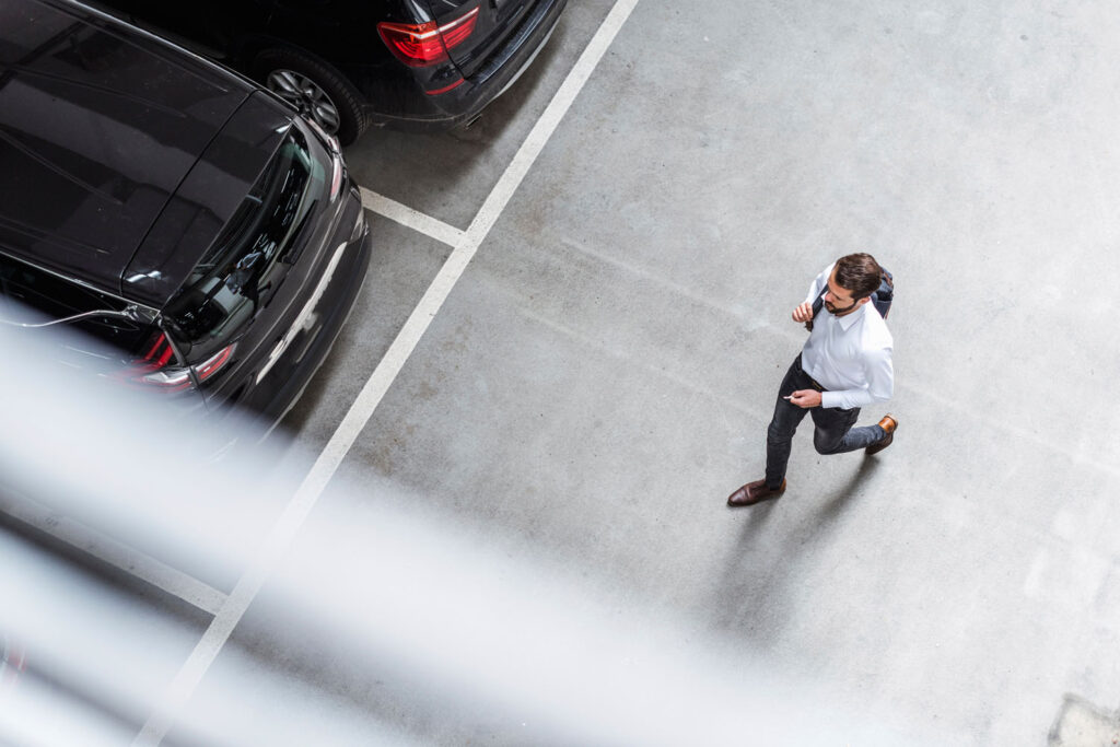 Young businessman with backpack on the go at parking garage