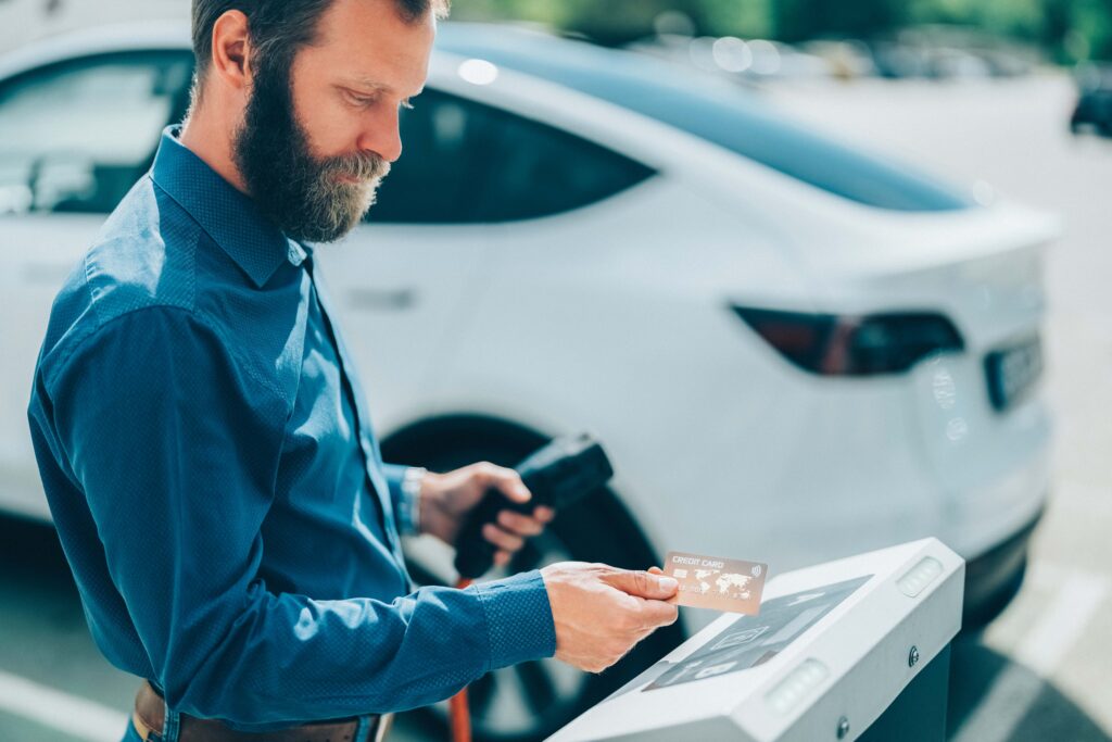 man at charging station paying with credit card